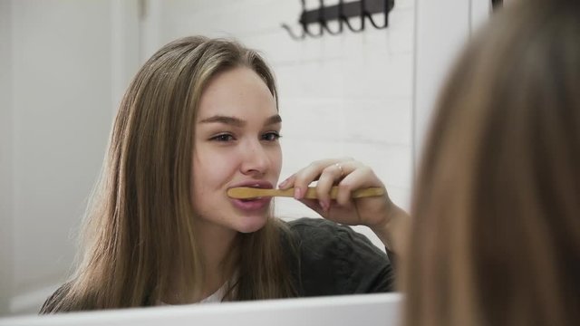 Young woman and a wooden tooth brush. Zero-waste lifestyle concept of replacing plastic landfill waste with eco-friendly options.