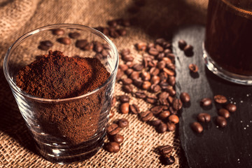 black coffee in a transparent glass Cup on a background of burlap. next to sugar, coffee beans and ground coffee. vintage