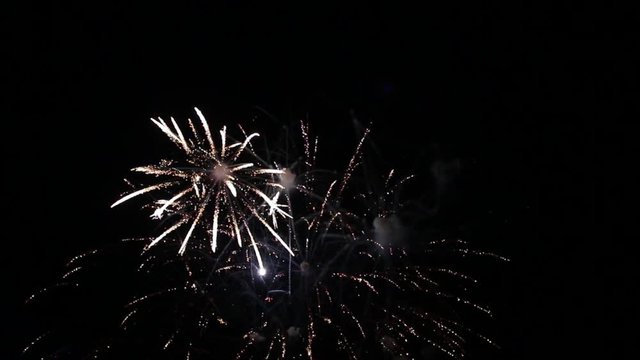 Bright colorful fireworks turn to multicolor bokeh lights at holiday dark summer night.