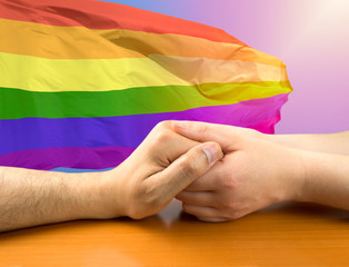 Two men shaking hands with a colorful flag in the background