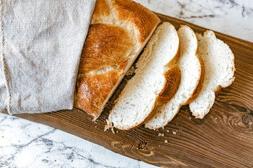 Homemade Jewish traditional challah bread on rustic wooden cutting board. Top view of warm fresh baked challah cut in slices