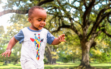 An African American toddler is playing outside on a sunny day