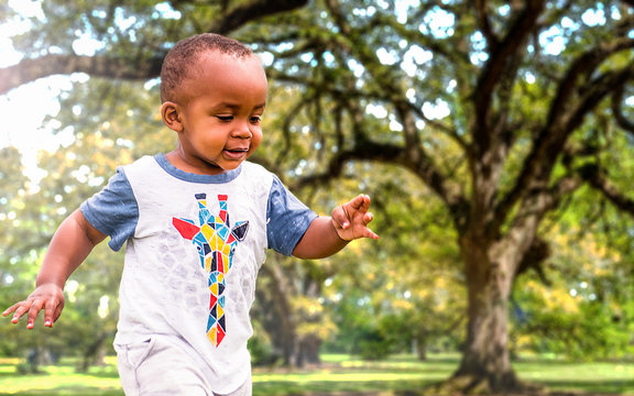 An African American Toddler Is Playing Outside On A Sunny Day