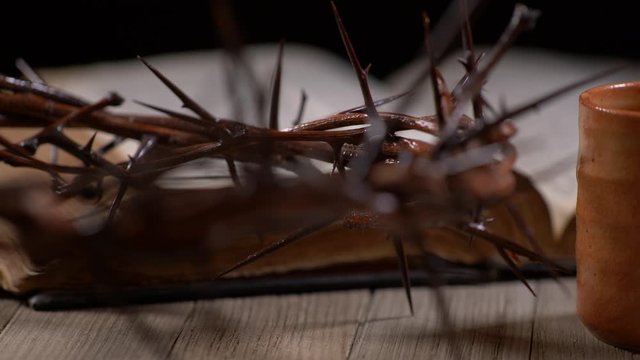 Cup being filled with wine with old Bible and Crown of Thorns panning right