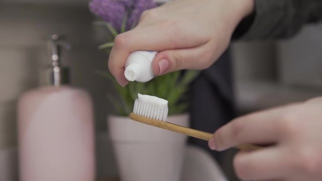 Close up of woman puts toothpaste on toothbrush