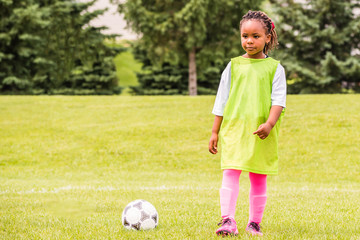 A young African American girl is learning how to play soccer on a sunny day	