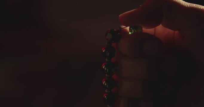 Close up footage of a person praying on his prayer beads