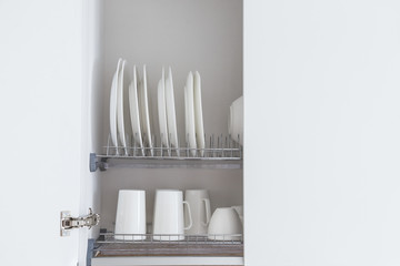 Dish drying metal rack with big nice white clean kitchenware. Traditional wall cabinet kitchen