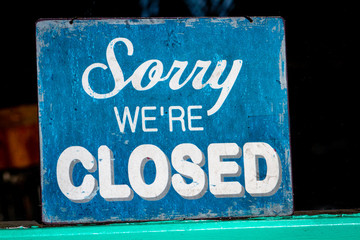 Sorry, we're closed sign standing in a shop window