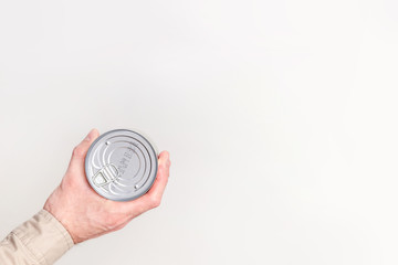 Canned food in man's hand close-up on white