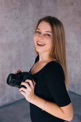 cheerful female photographer smiling and posing with camera