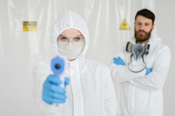 Medical professionals in protective clothing measuring contactless fever at Covid-19 test center...