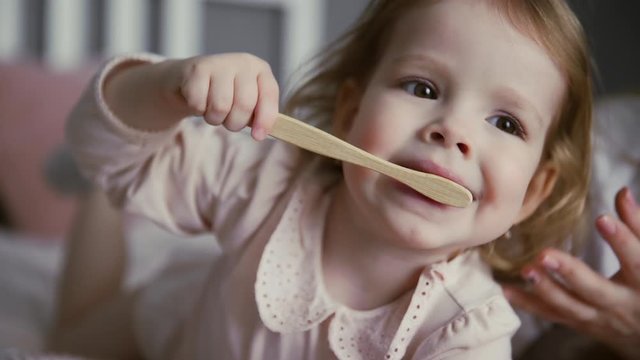 Closeup of a little girl brushing her teeth with a bamboo toothbrush