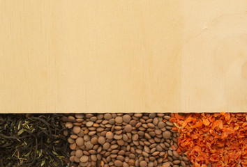 Scattered dry ingredients: beans, dry carrots, tea on the background of a wooden texture. Free space for text. The concept of food. Mock Up.