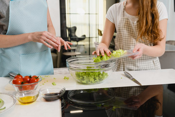 Obraz na płótnie Canvas Women put green salad at bowl indoors
