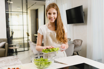 Obraz na płótnie Canvas Teen happy girl make salad at home