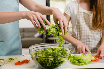 Hands pour greens for salad in bowl