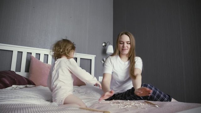 Active young mom babysiter and cute little kid daughter playing in bedroom. Happy litte girl plays with wooden bamboo toothbrush and cotton swabs