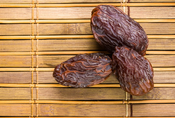 Big luxury dried date fruit on the bamboo mat, kurma ramadan kareem concept, close up.