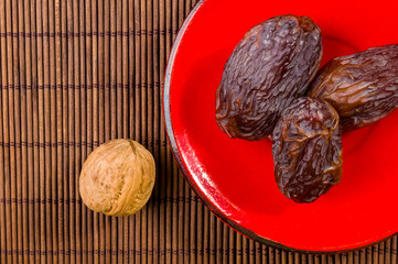 Big luxury dried date fruit in bowls on the bamboo mat, kurma ramadan kareem concept, close up.