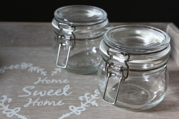 Food storage - two empty glass jars for coffee beans or tea on gray wooden tray