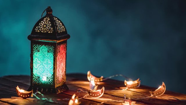 Ramadan Lantern with Colorful Light Glowing at Night and Glittering with Bokeh Lights on Ground. Festive Greeting Card, Invitation for Muslim Holy Month Ramadan Kareem. Blue Dark background – Stop Mot