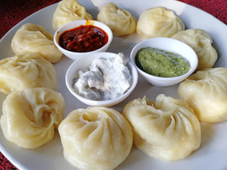 steamed Nepali traditional momos dumplings are served with different sauces. Close up, side view