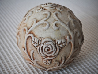 a porcelain beige ball decorated with floral ornaments on a light background