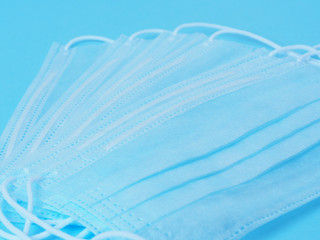 Obraz premium Surgical protective face masks are laid out on a blue background. Concept of protection against viruses and bacteria.