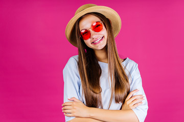 the summer clerk in a straw hat shrugs broadly smiling. background pink