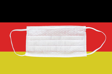 Obraz premium Coronavirus in Germany. Medical mask on the background of the flag