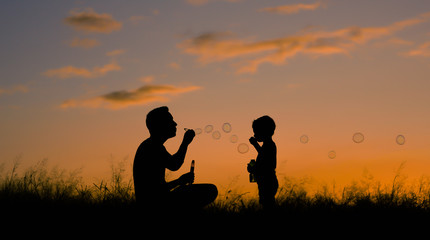 Fototapeta na wymiar Father son playing in the park blowing bubbles. Family lifestyle concept. 