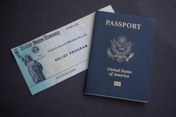 Passport of United States of America next to the Stimulus Check relief program on flag of USA background.
