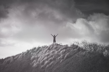 Victory on top a mountain. Man feeling strong, and inspired  with arms up to the sky. 