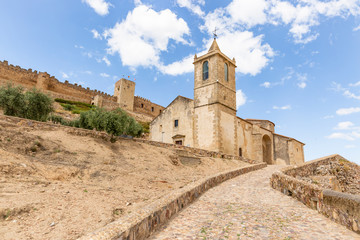 Fototapeta na wymiar Santiago church with the medieval castle in the background in Medellin, comarca de Vegas Altas, province of Badajoz, Extremadura, Spain