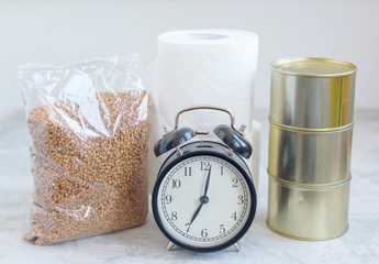 alarm clock and anti-crisis kit - buckwheat, toilet paper rolls and canned food, due to the pandemic and the quarantine of the coronavirus