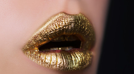 Gold lips. Golden Paint from the lips. Golden lips on beautiful model girls mouth. Make-up. Beauty...