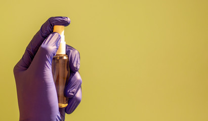 A hand in a green medical glove applying a disinfectant or antiseptic gel to protect against infectious viruses, bacteria and germs.