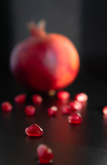 Closeup pomegranate seeds and pomegranate fruit in the background on a dark. Selective focus Contrast.