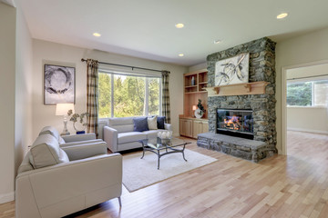 Living room with stone fireplace and light hardwood floor and sliding door to the back yard.