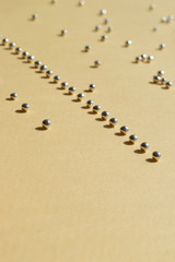 Fototapeta na wymiar Rows of silver bakery beads with sunny shadows. Vertical photo with empty space down for necessary use. Geometry lines of sugar pearls on the light yellow background. Trendy concept idea