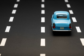 Fototapeta na wymiar Rear view of a blue toy car on an asphalt road