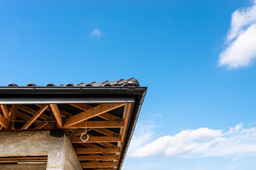 Obraz premium The roof of a single-family house covered with a new ceramic tile in anthracite against the blue sky, visible trusses. 