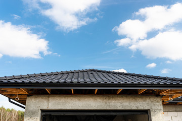 The roof of a single-family house covered with a new ceramic tile in anthracite against the blue...