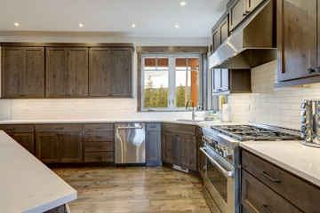 Luxury dark wood rich kitchen interior with white subway tiles backsplash and quarts countertop.