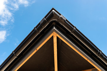 Fototapeta premium The roof of a single-family house covered with a new ceramic tile in anthracite against the blue sky, visible trusses. 