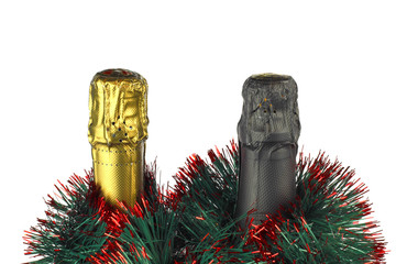 The neck of two bottles of champagne next to a branch of a Christmas tree on a light background.