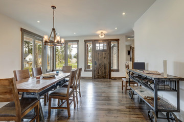 Open bright living room with long rustic wooden table and metal modern and cart as a side table.