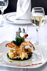 plato de camarones asados a la mantequilla con copa de vino blanco, sobre una mesa de restaurante, con vista panorámica a la ciudad y mantelería blanca  