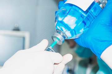 Doctor holds syringe and gains solution from the bottle